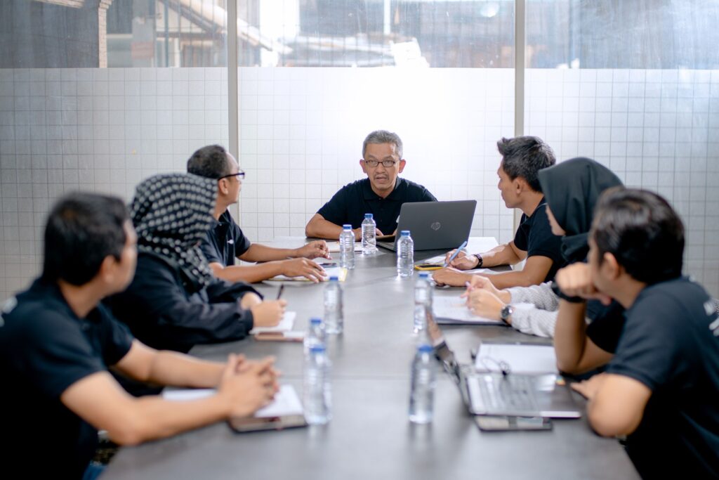 Professional team meeting around a conference table in an office setting.