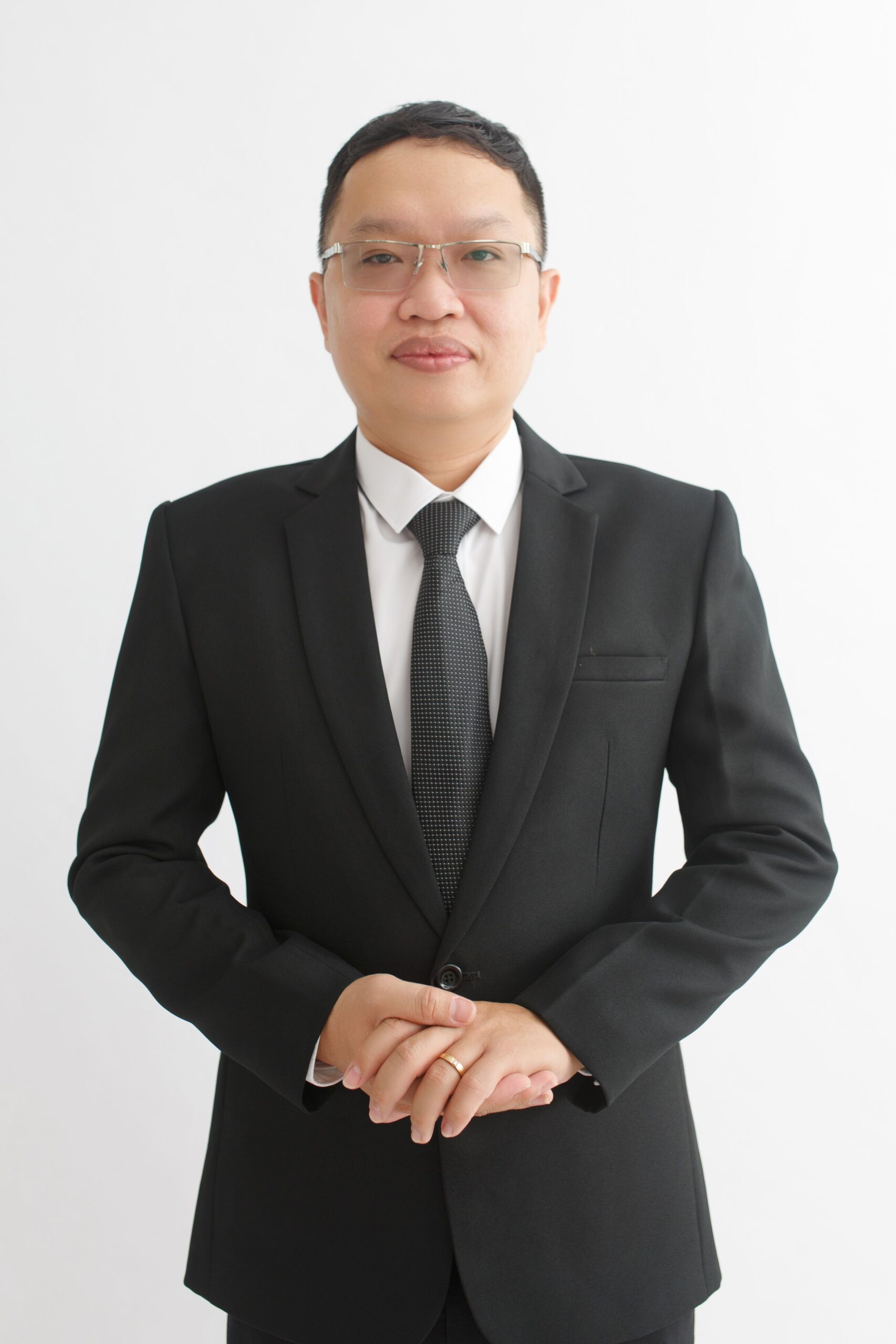 Portrait of a businessman in a black suit standing against a white background, exuding confidence.