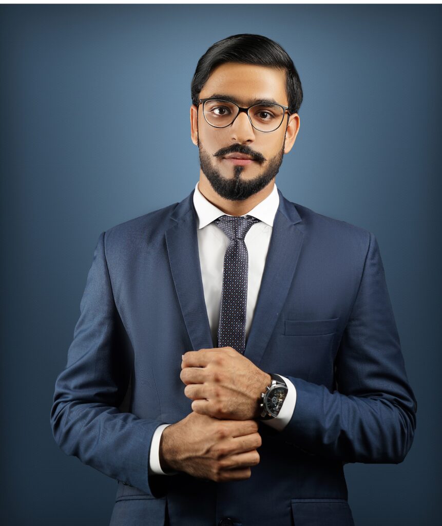 Confident man with beard and glasses wearing a suit and tie in a studio setting.
